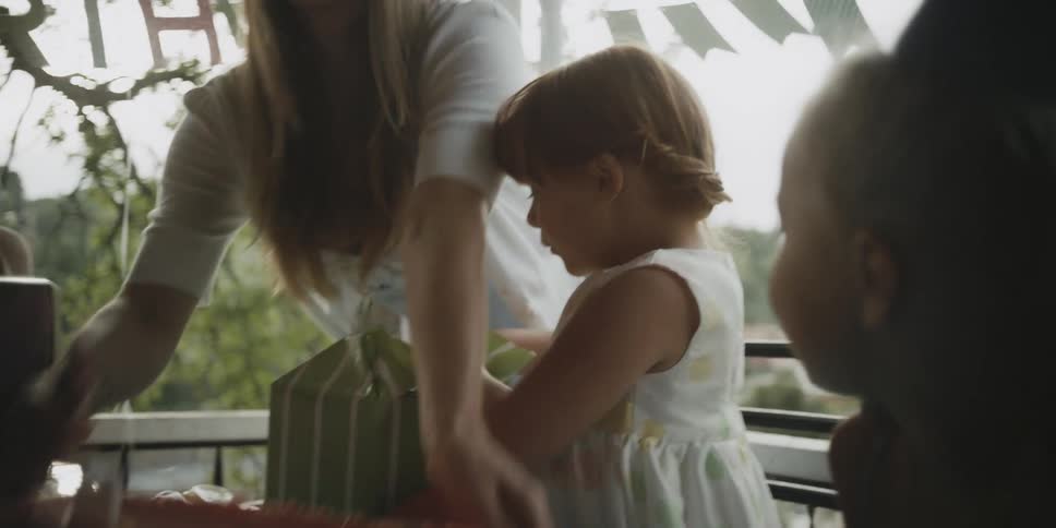 A girl opens a gift at a birthday party