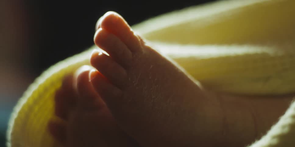 A baby wrapped in blankets wiggles its feet