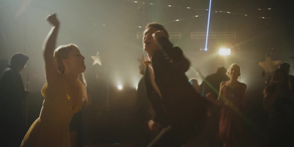 A large group of people inside a gym dancing with flashing lights and lasers