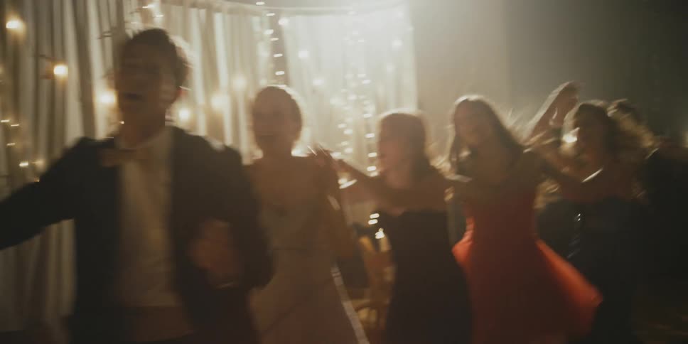 Teenagers dance a conga line at a prom