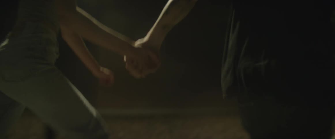 Two people run while holding hands at night