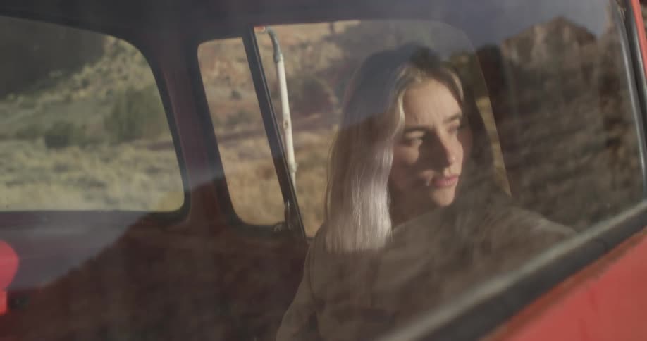 A woman is riding in a vehicle looking out of the window