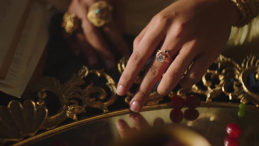 A woman runs her fingers along a ornate gold mirror