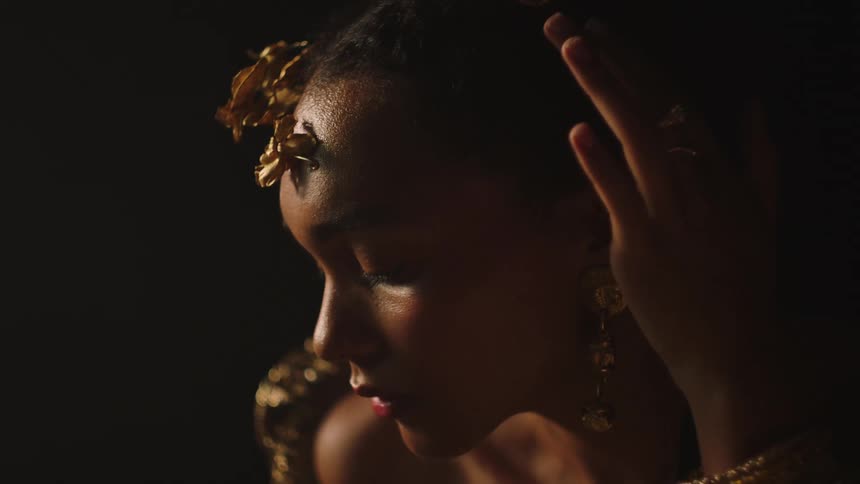 A model poses with gold jewelry adorning her head and fingers
