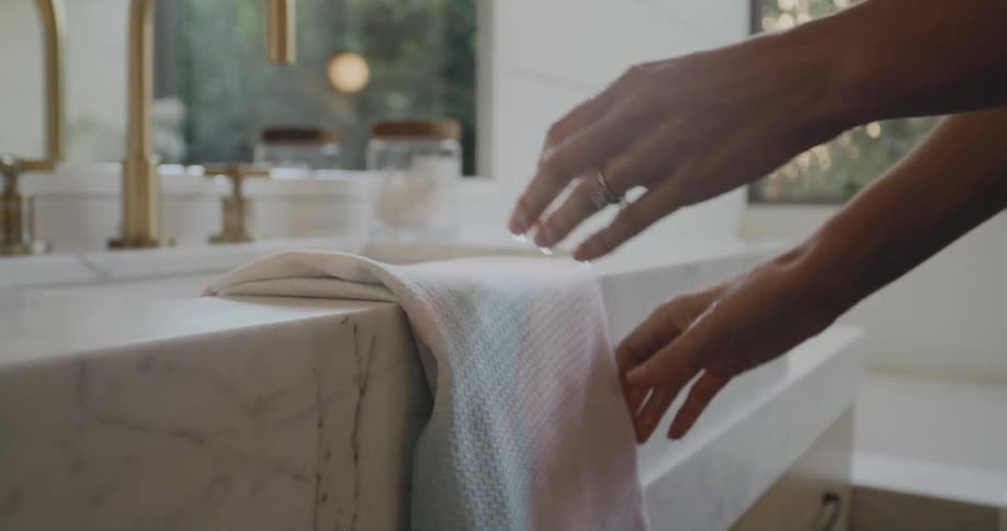 A woman at home dries her hands after washing them