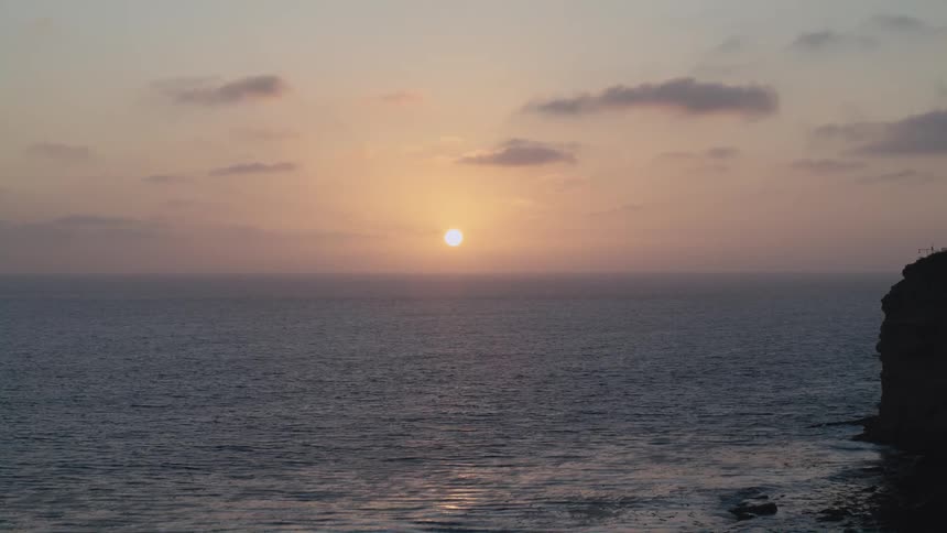 Aerial view of the sun setting above the ocean water