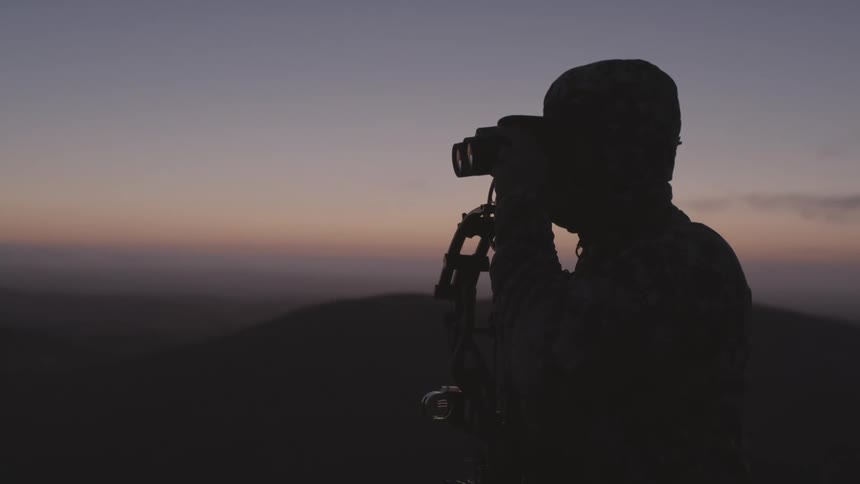 A man is watching the sunset with binoculars