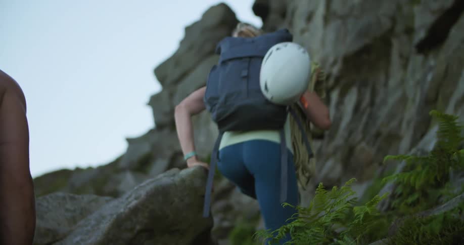 A man and woman carry their equipment up the mountain