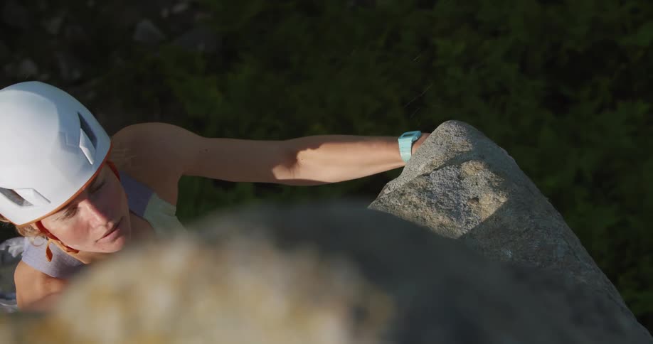 Female rock climber has chalk covered hands as she climbs cliff