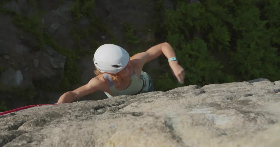 A woman climbing up rocks on a cliff