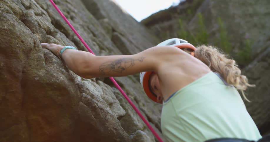 Female climber pulling up a rock face