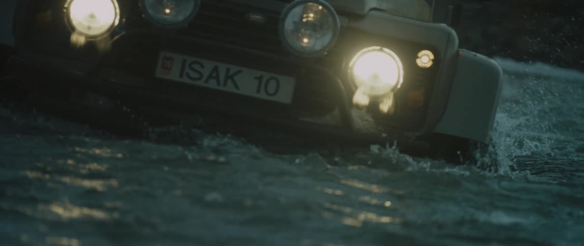 A jeep drives through rough river water