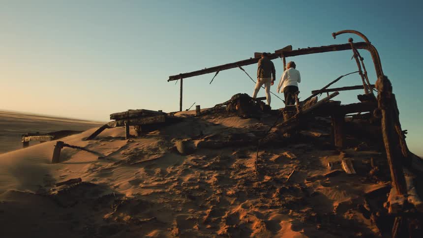 Two people explore an ancient desert shipwreck