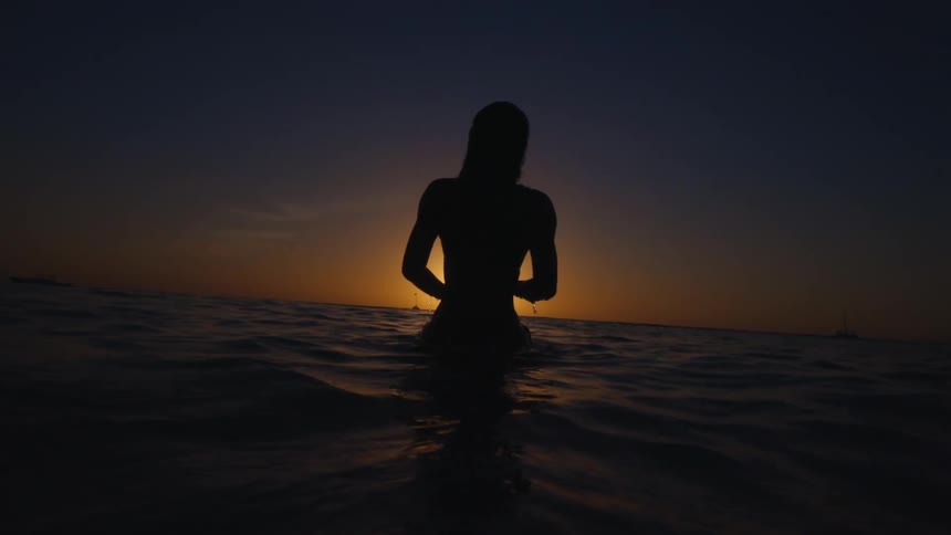 A woman in the ocean stands up