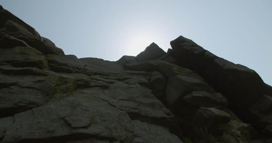 The sun shines behind rocky hill