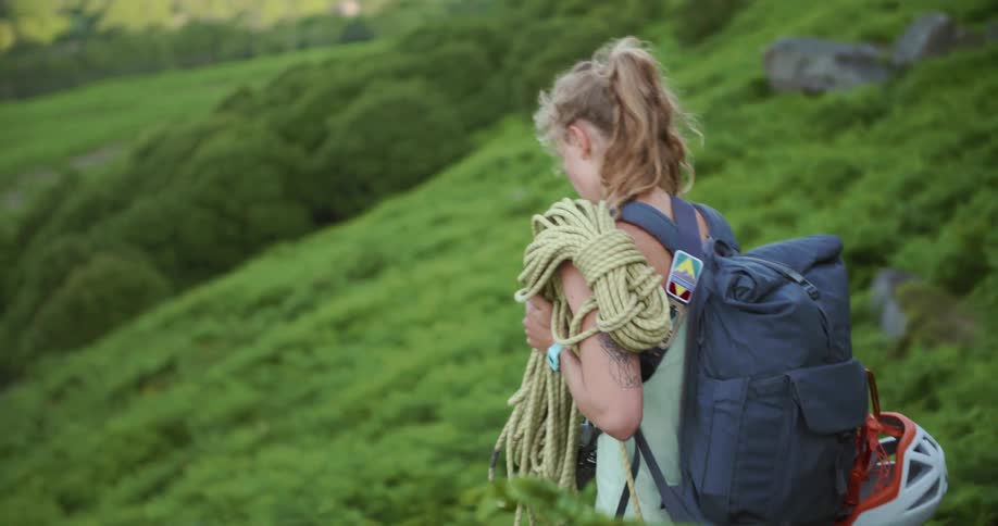 Climbers walk down slope carrying rope