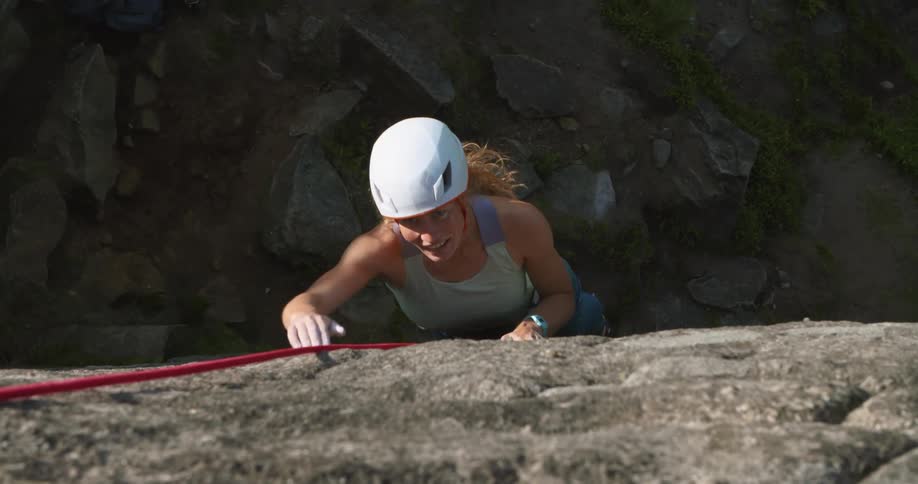 A woman is rock climbing up a mountain in spring