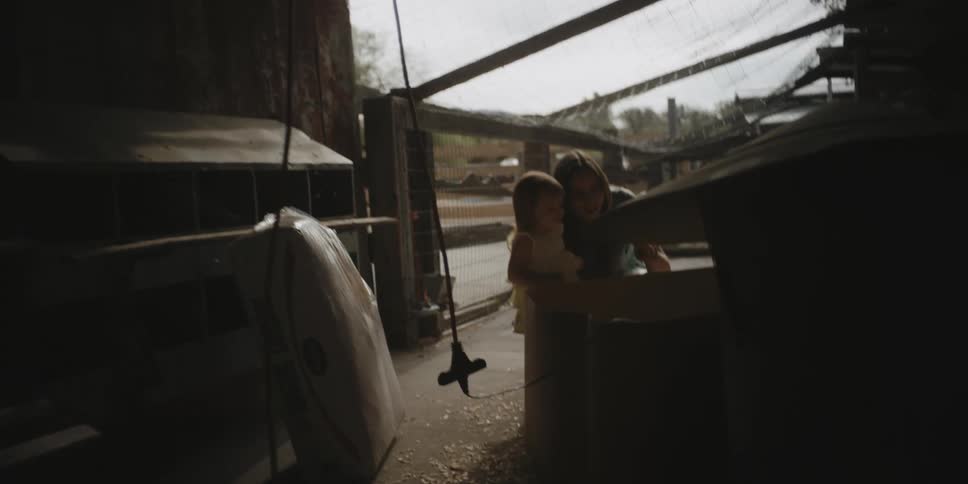 A woman shows a young girl animals in a pen