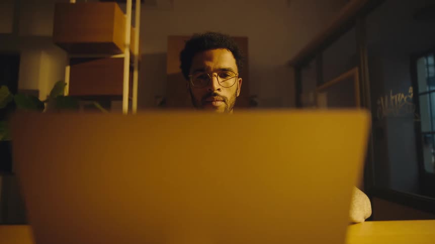 camera revolves around man sitting at table opening laptop
