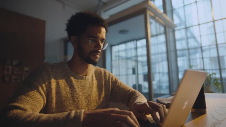 camera moves from laptop replaceable screen to man working on laptop