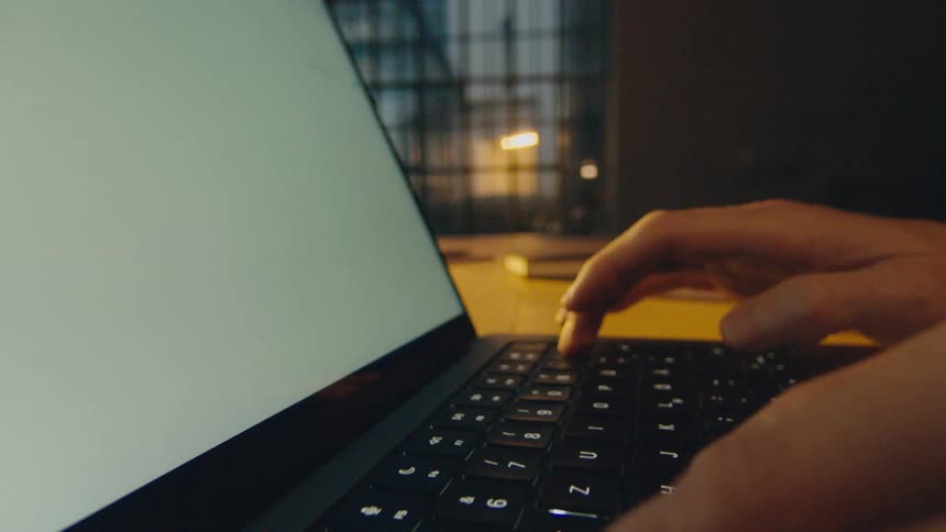 camera tracks back through hands typing on keyboard