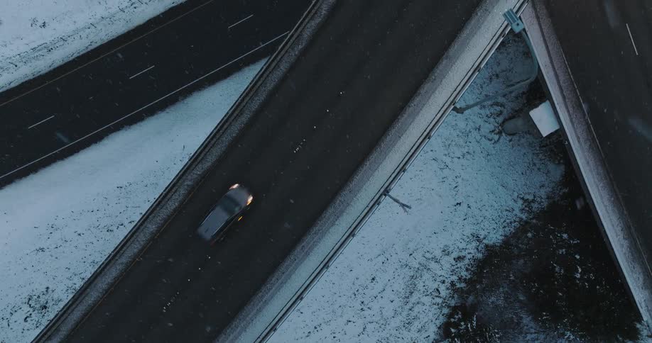 Vehicles move across a slushy elevated highway as it snows
