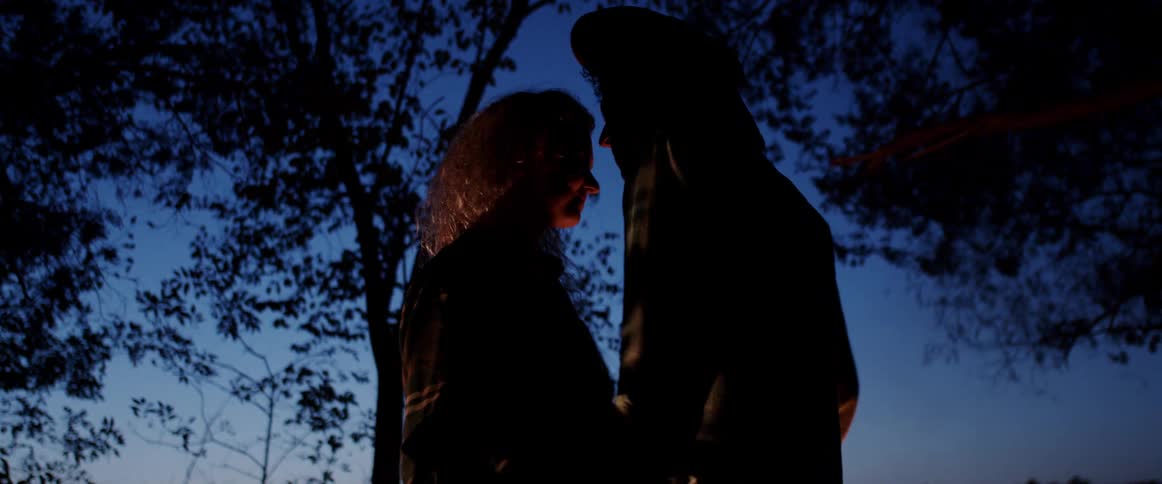A man and woman dance under trees at night