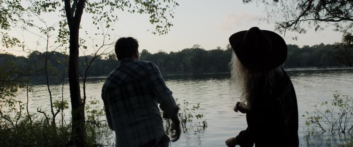 A man and woman talk as they skip rocks in a lake