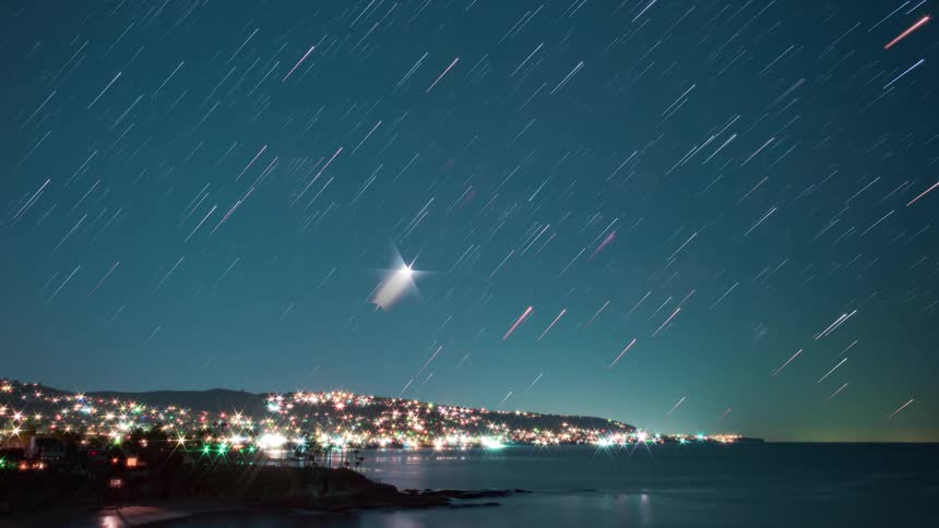 The stars in a coastal night sky move leaving blur lines