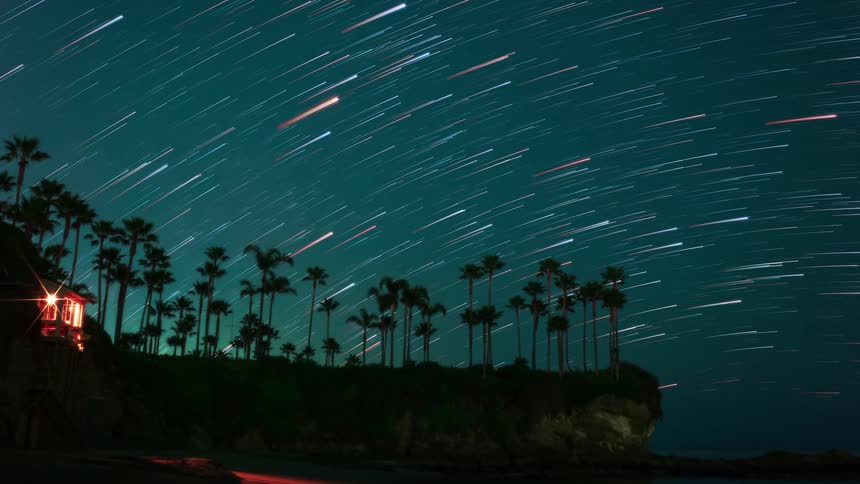 Stars in the night sky over a building and palm trees
