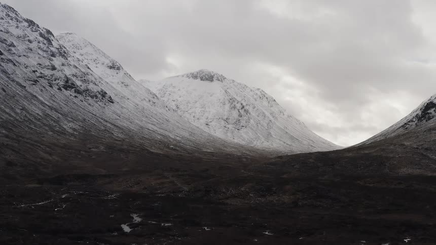 Mountain slopes dusted with snow under a cloudy sky