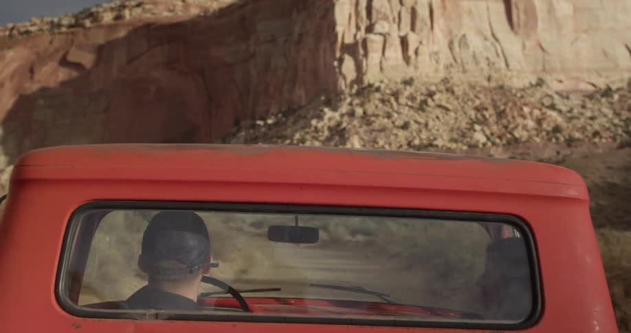 Two people are in a traveling pickup truck near a canyon