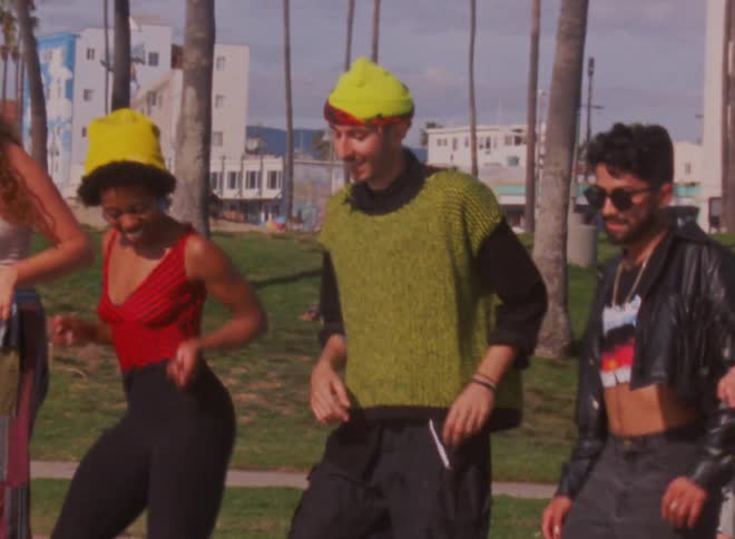 A group of people line dancing on roller skates near the beach