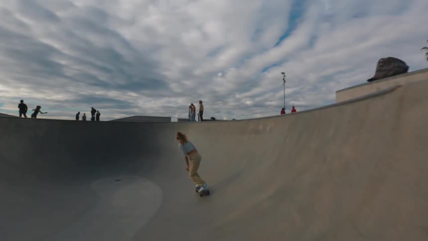 A girl races a skateboard in the skate park