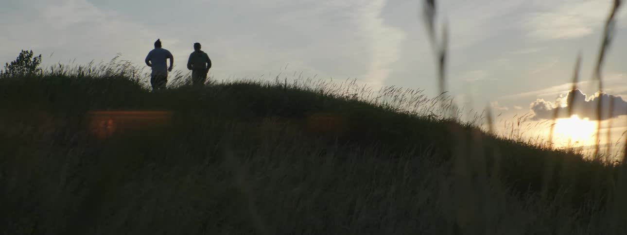 Two men jog up a hill together
