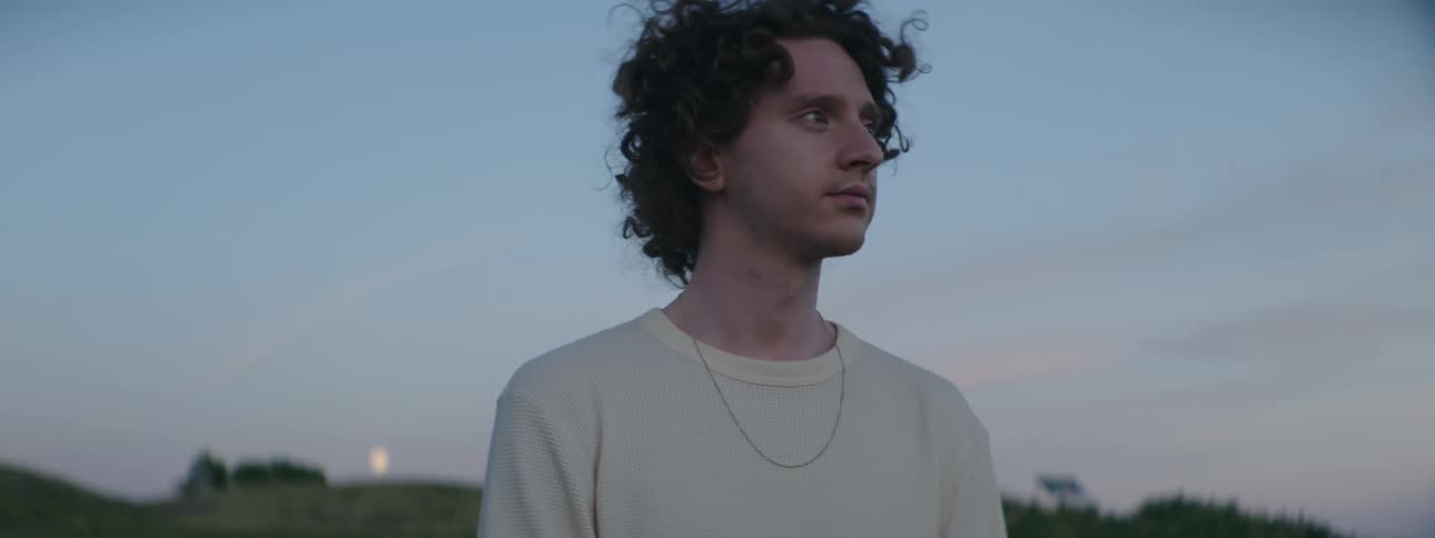 A man stands outside at sunset