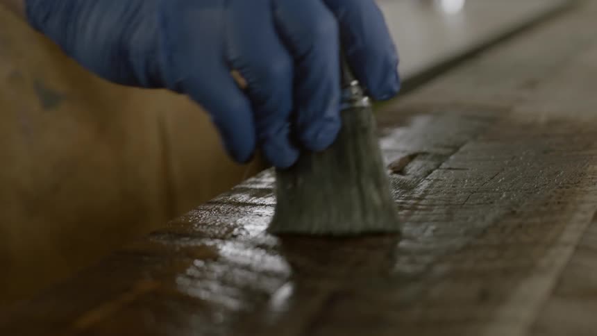 A person stains a piece of wood