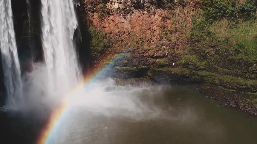 A waterfall is falling and creating a rainbow below