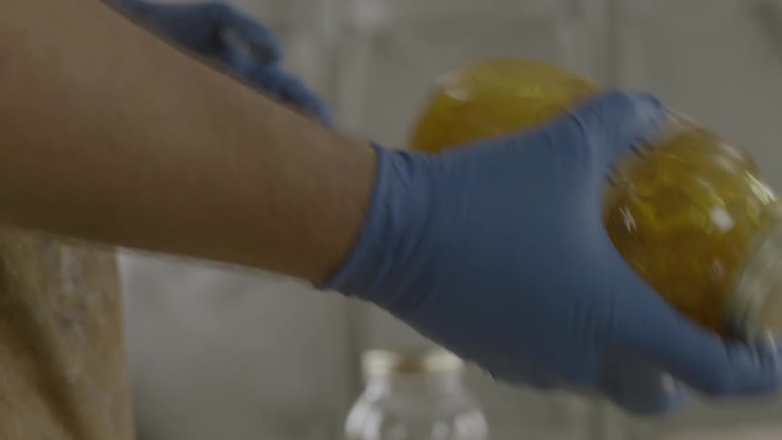 Persons shaking a closed jar while wearing protective gloves