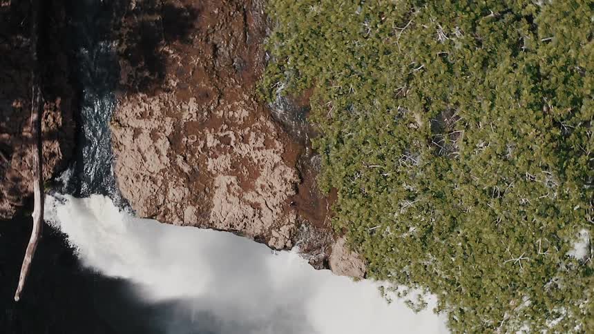 Aerial view moving up and away from a waterfall