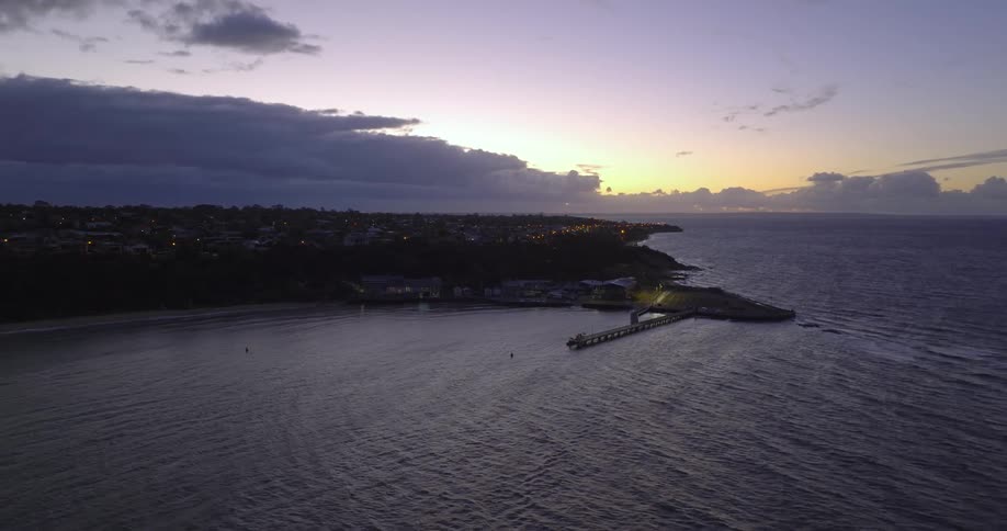 An aerial view of a dock on a beach at sunrise