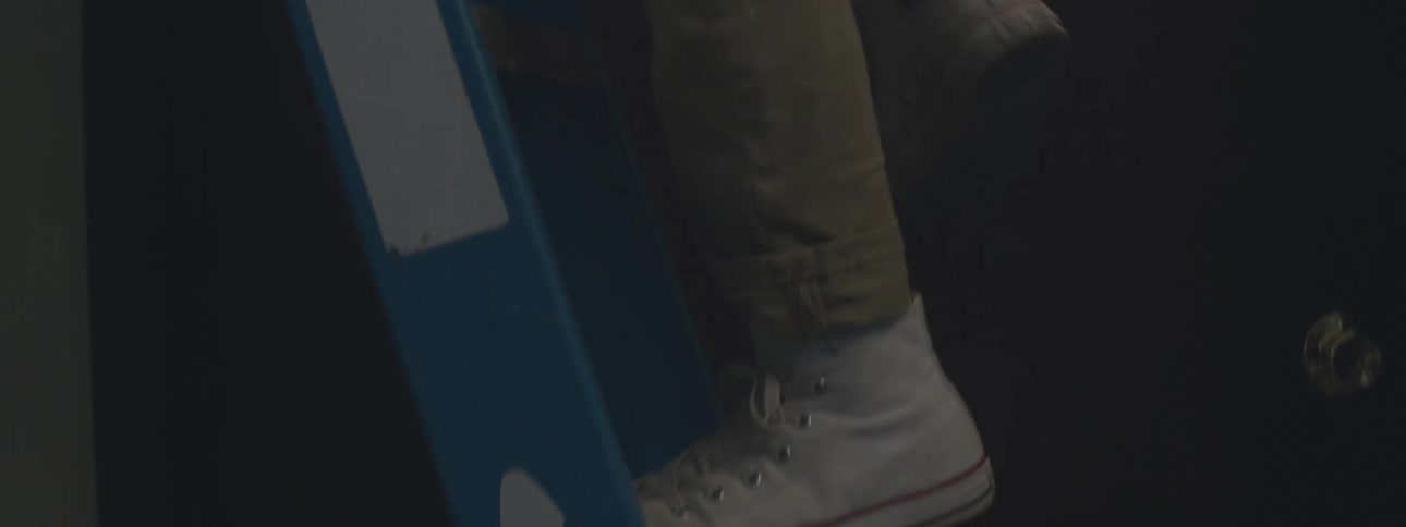 Person wearing jacket and holding flashlight climbs blue stepladder