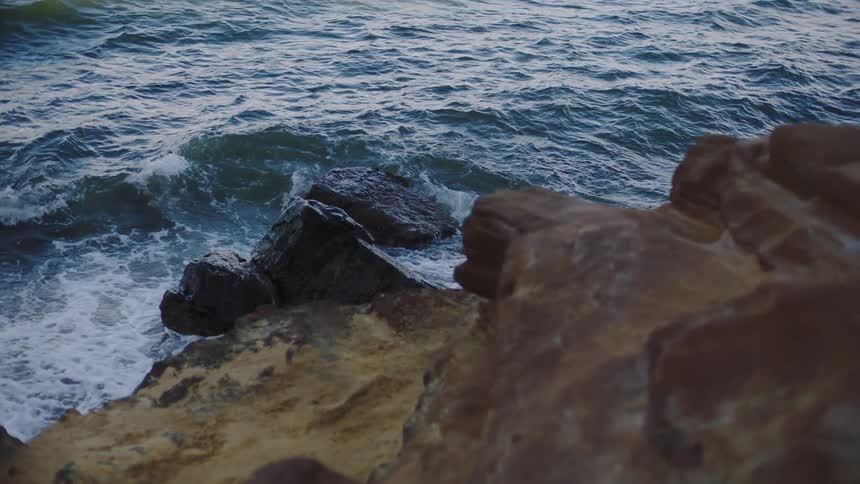 Waves crash against rocky shore sending spray into the air