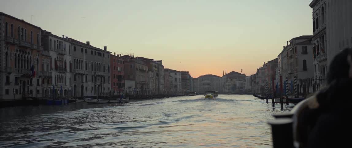 Boats moving down the Grand Canal in Venice, Italy at sunset.