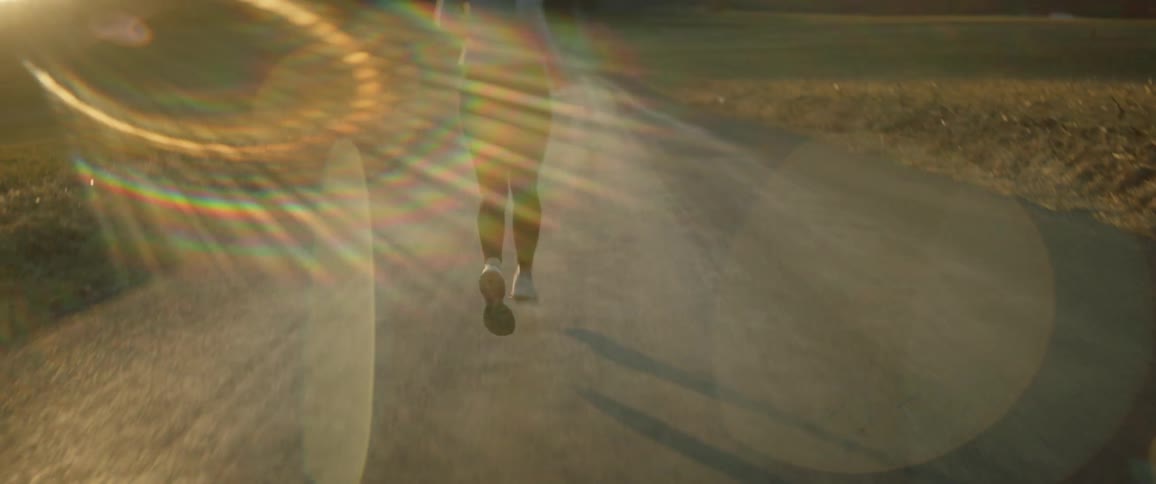 Woman with ponytail gray sweatshirt and black leggings run on country road