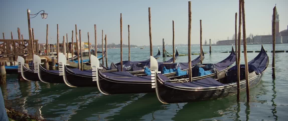 A row of gondolas moored at a dock along the Grand Canal in Venice, Italy