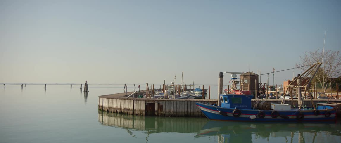 Boats parked along a pier on Burano Island, Venice, Italy