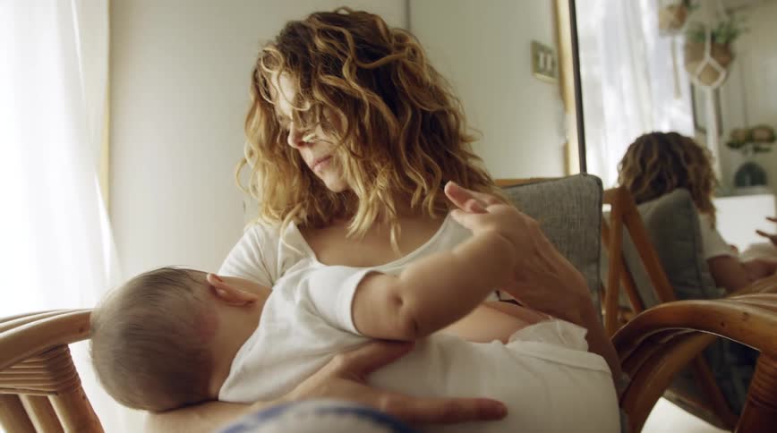 A woman at home sits and holds her baby