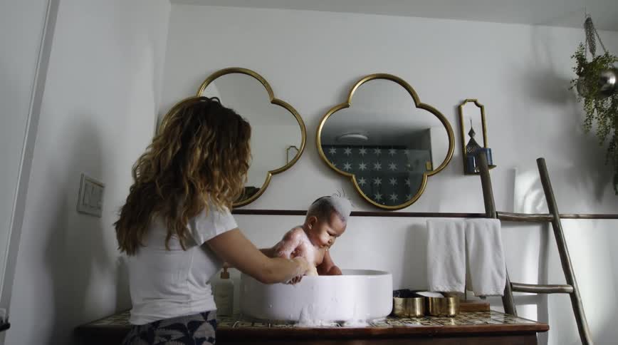A mother is bathing her son in the sink