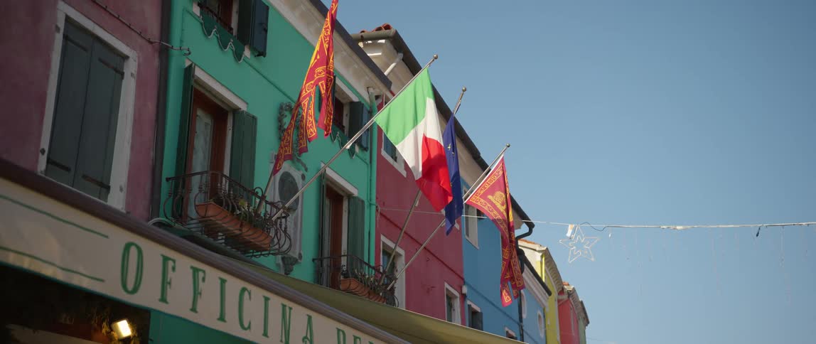 Flags and window boxes hanging from colorful buildings on Burano Island, Venice, Italy
